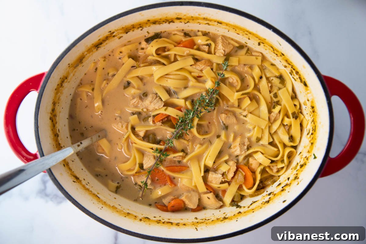 Comforting Creamy Chicken Noodle Soup 6 An inviting overhead view of a large pot of creamy chicken noodle soup, with a ladle ready for serving, highlighting its rich texture.