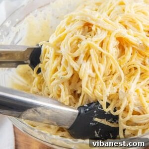 bowl of creamy alfredo sauce and pasta with tongs