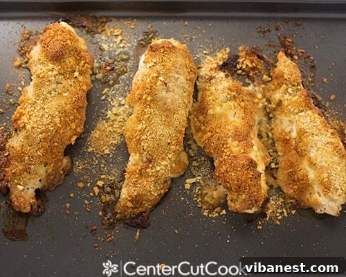 Parmesan crusted chicken slices on a cutting board. Close-up view of perfectly breaded and cooked Parmesan crusted chicken slices on a cutting board, ready for serving.
