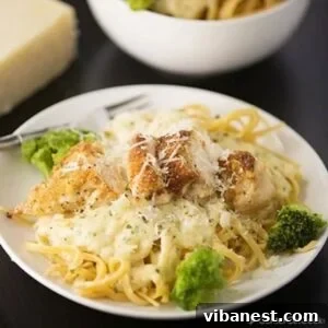Plate of Parmesan Crusted Chicken Alfredo, a hearty and satisfying meal with green garnish.