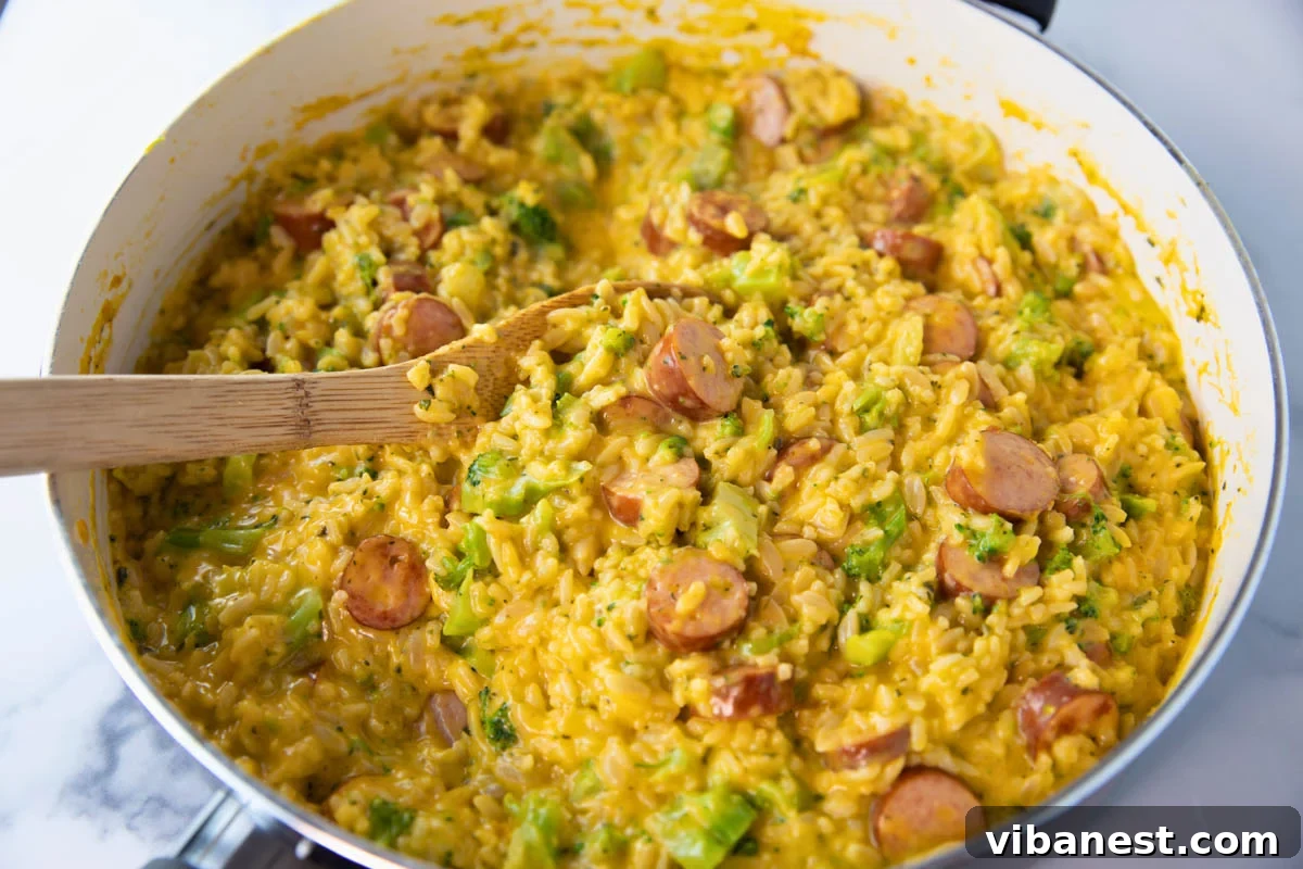 Hearty Cheesy Sausage and Rice Skillet 6 skillet of cheesy sausage and rice skillet with a wooden spoon for stirring