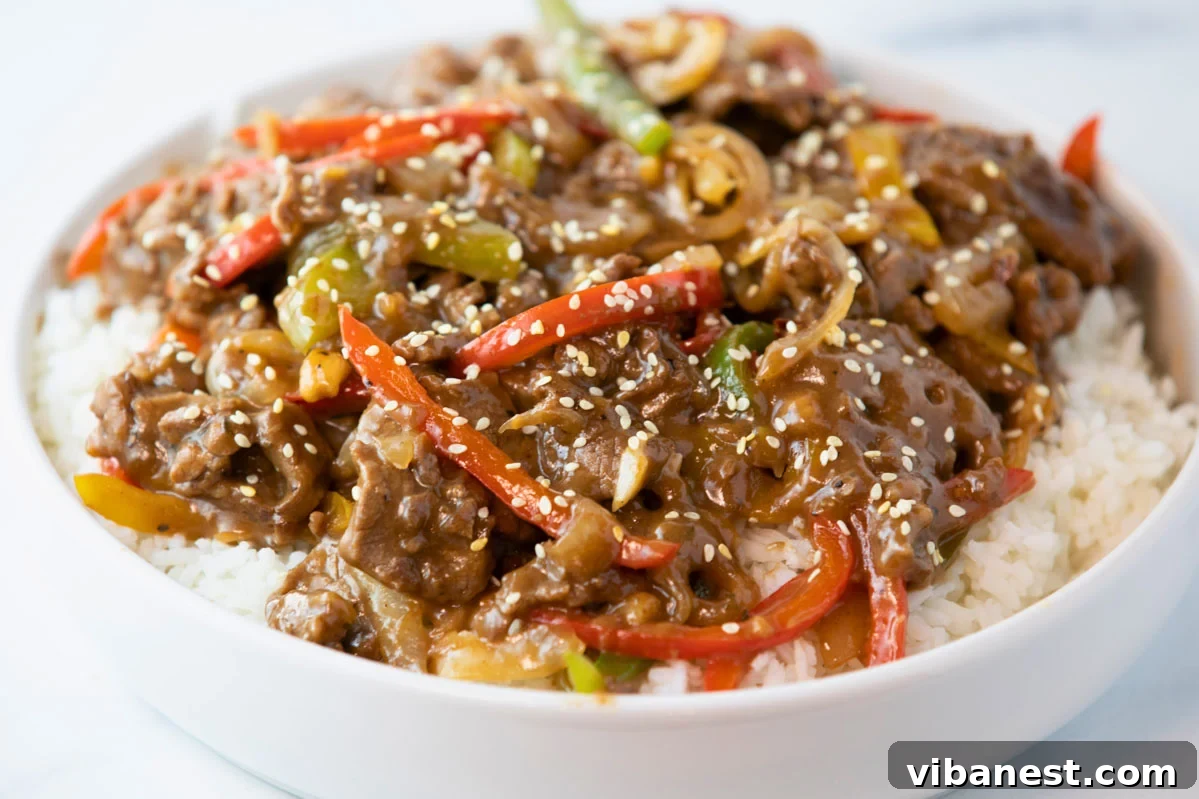 Sizzling Pepper Steak with Onions 10 Bowl of pepper steak and onions over rice, ready to be eaten