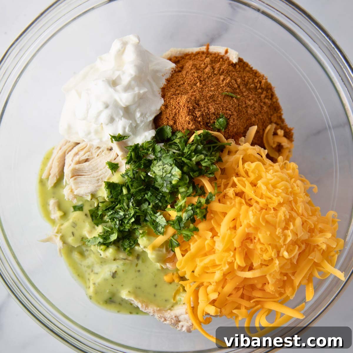 Crispy Air Fryer Chicken Taquitos 3 Overhead shot of fresh ingredients for air fryer taquitos in a mixing bowl including shredded chicken, cheese, and salsa