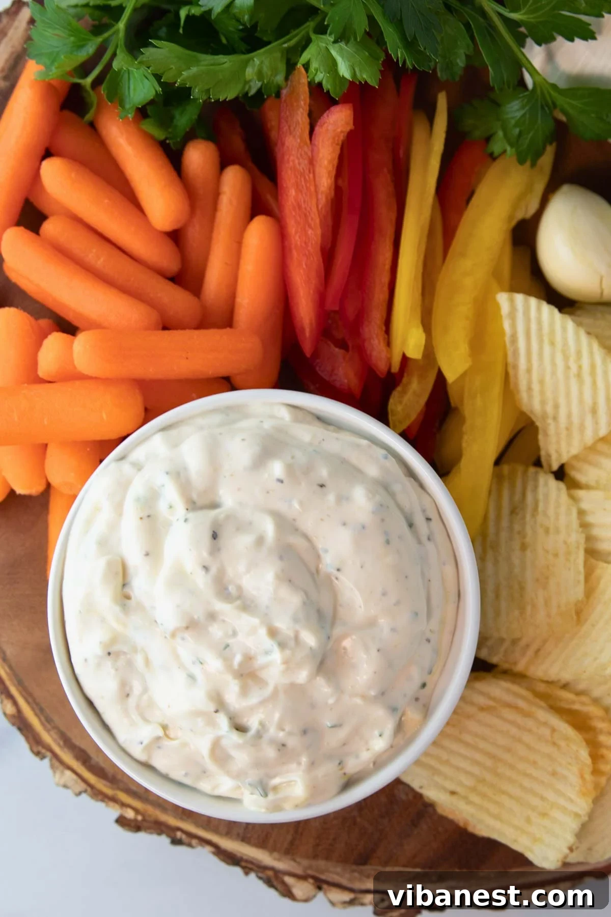Velvet Garlic Delight 4 An inviting overhead view of a bowl of creamy garlic dip, surrounded by an assortment of fresh vegetables and crispy chips, illustrating serving suggestions.