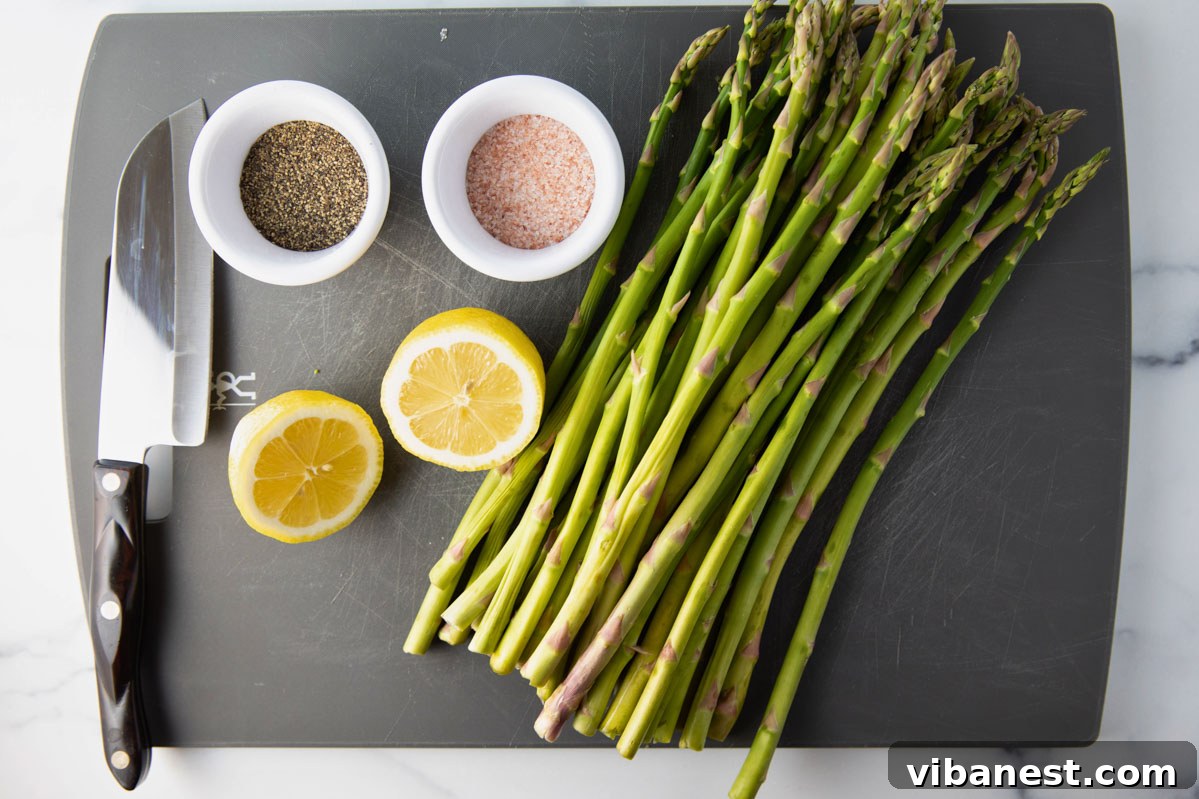 Effortless Grilled Asparagus 3 Overhead view of a cutting board with fresh asparagus, lemon halves, olive oil, and seasonings, ready for preparation.