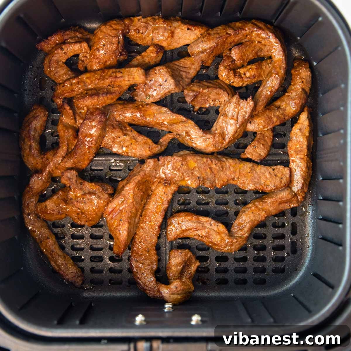 Air Fryer Fajita Burrito Steak 4 Overhead view of air fryer basket filled with perfectly cooked, tender strips of air fryer steak, ready for burritos and fajitas.