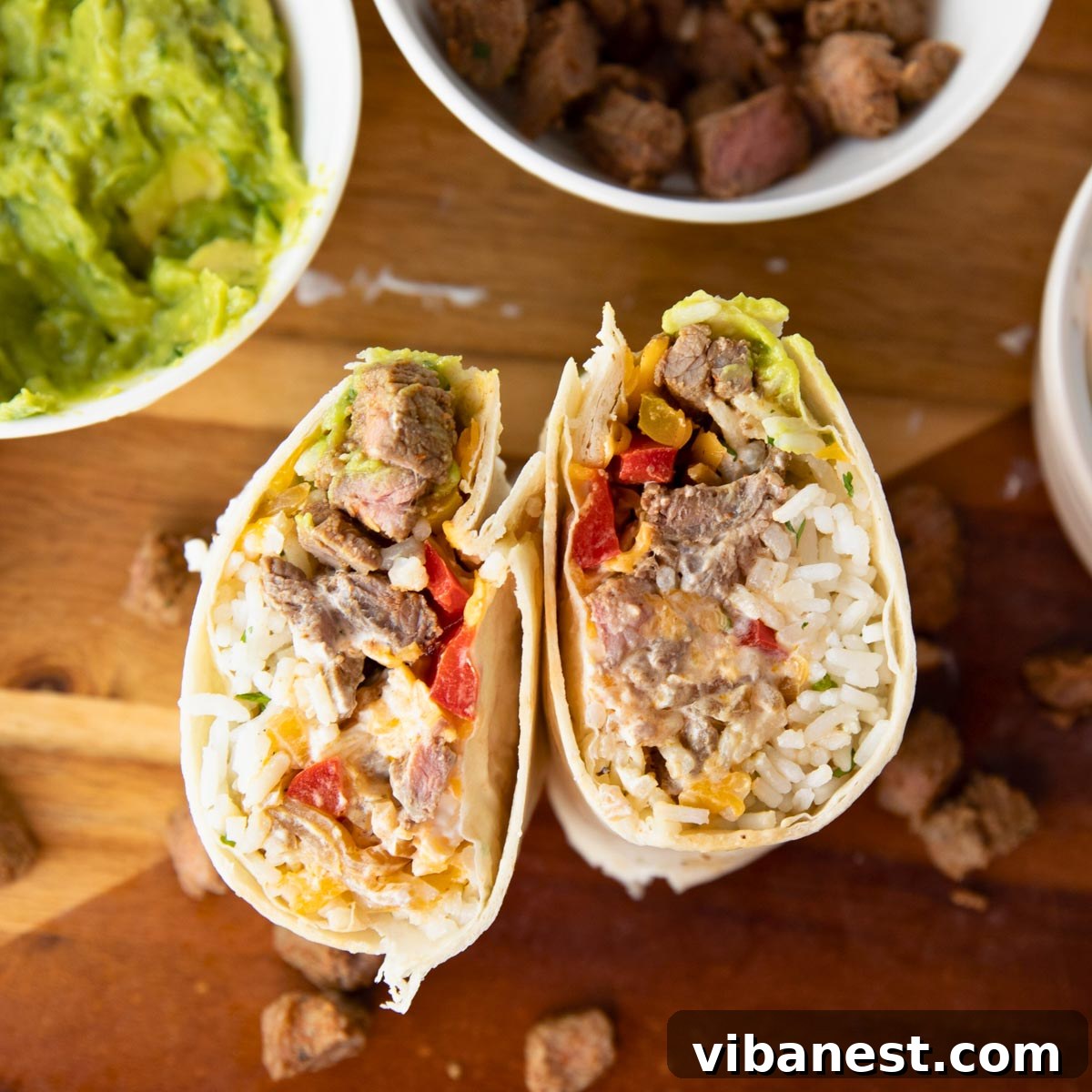 Simple Steak Burrito Delight 4 Overhead view of a finished easy steak burrito alongside bowls of guacamole and steak, creating a tempting spread.