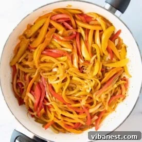 Overhead shot of a skillet filled with colorful, sizzling fajita veggies.