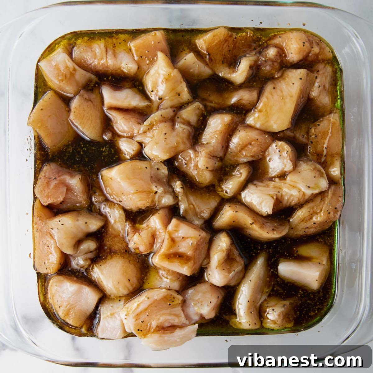 Char-Grilled BBQ Chicken Skewers 4 Close-up of cubed chicken breast marinating in a flavorful liquid in a bowl