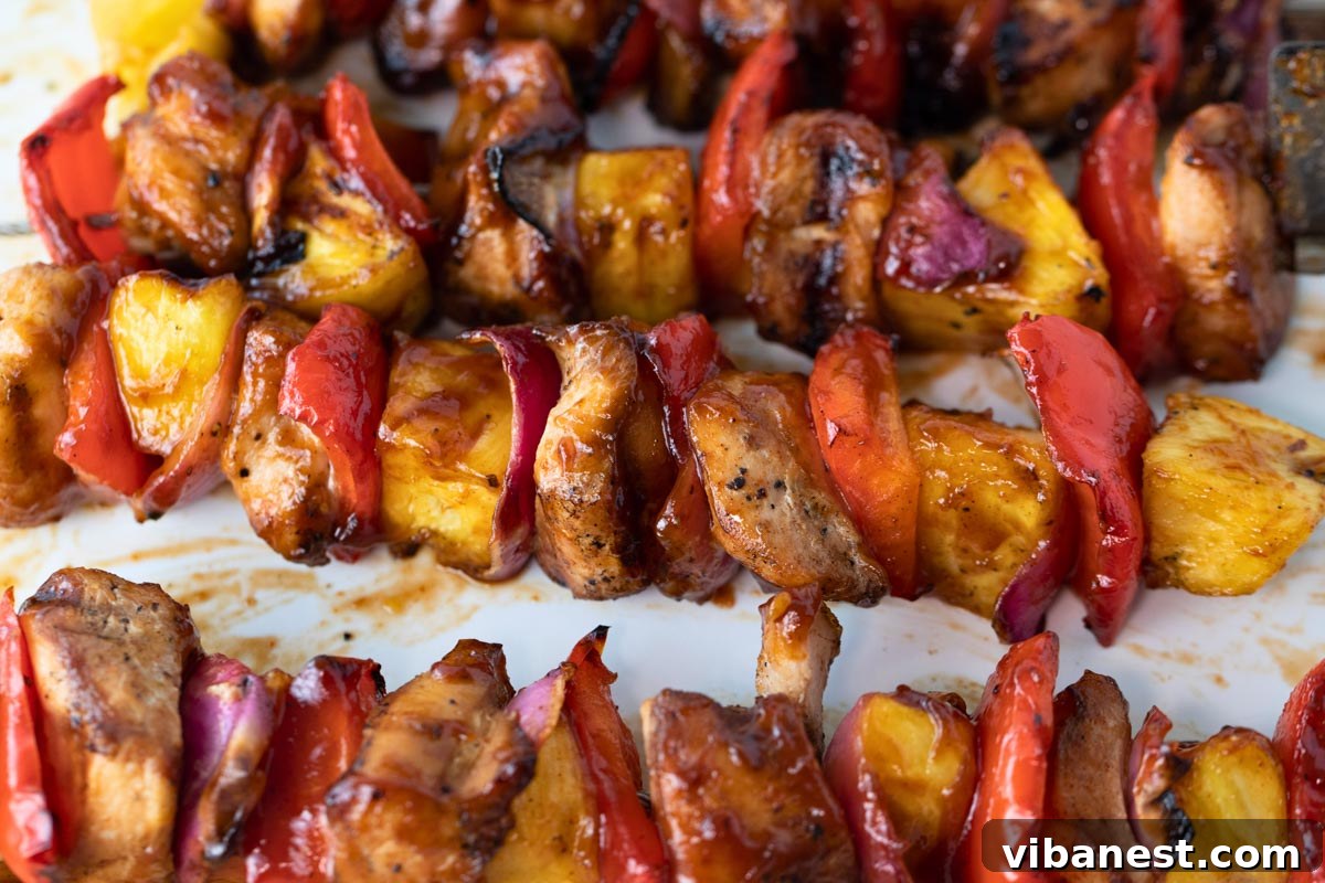 Char-Grilled BBQ Chicken Skewers 9 Close-up of a single perfectly grilled BBQ chicken kabob on a white plate, showcasing the caramelized sauce and vibrant ingredients