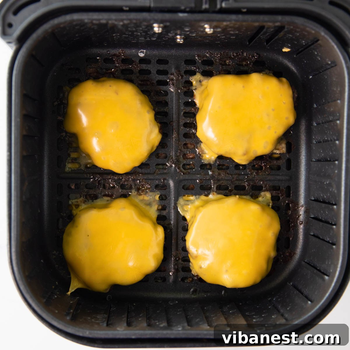 Air Fryer Cheeseburger Perfection 2 cheeseburger in the air fryer, garnished with fresh lettuce and tomato