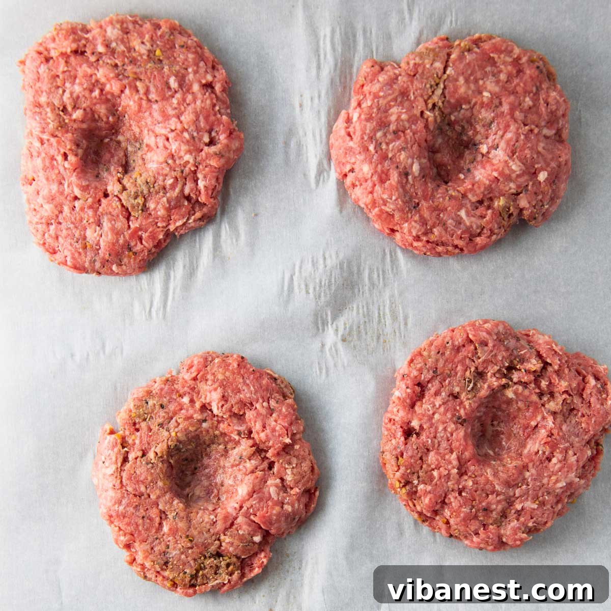 Air Fryer Cheeseburger Perfection 7 raw hamburger patties with a dimple in the center to prevent shrinking while cooking.
