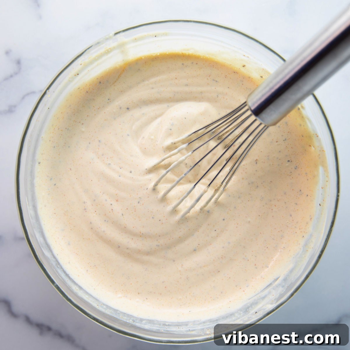 Quick Creamy Tuna Macaroni Salad 6 A bowl of creamy, yellow dressing made with mayonnaise, mustard, and spices, prepared for the tuna macaroni salad.