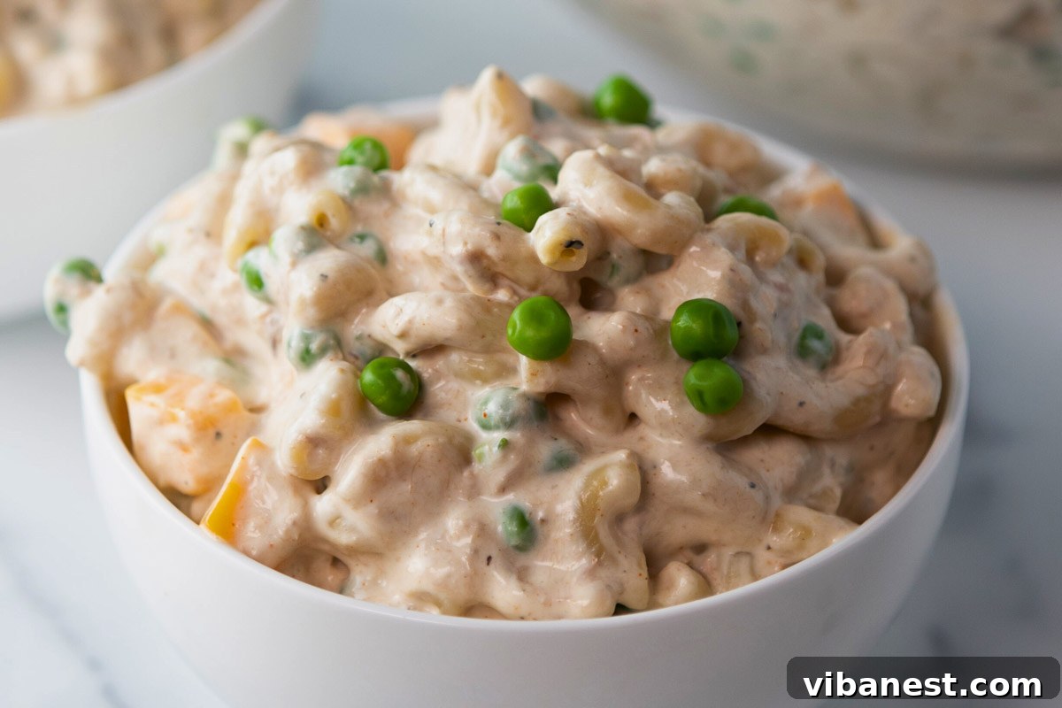 Quick Creamy Tuna Macaroni Salad 7 A close-up shot of the finished tuna macaroni salad in a bowl, showcasing the macaroni, tuna, peas, and cheddar coated in a creamy dressing.