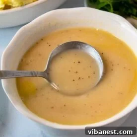 Sides That Make Your Ribs Sing 17 homemade turkey gravy in a small bowl with a lady,, perfect for thanksgiving dinner.