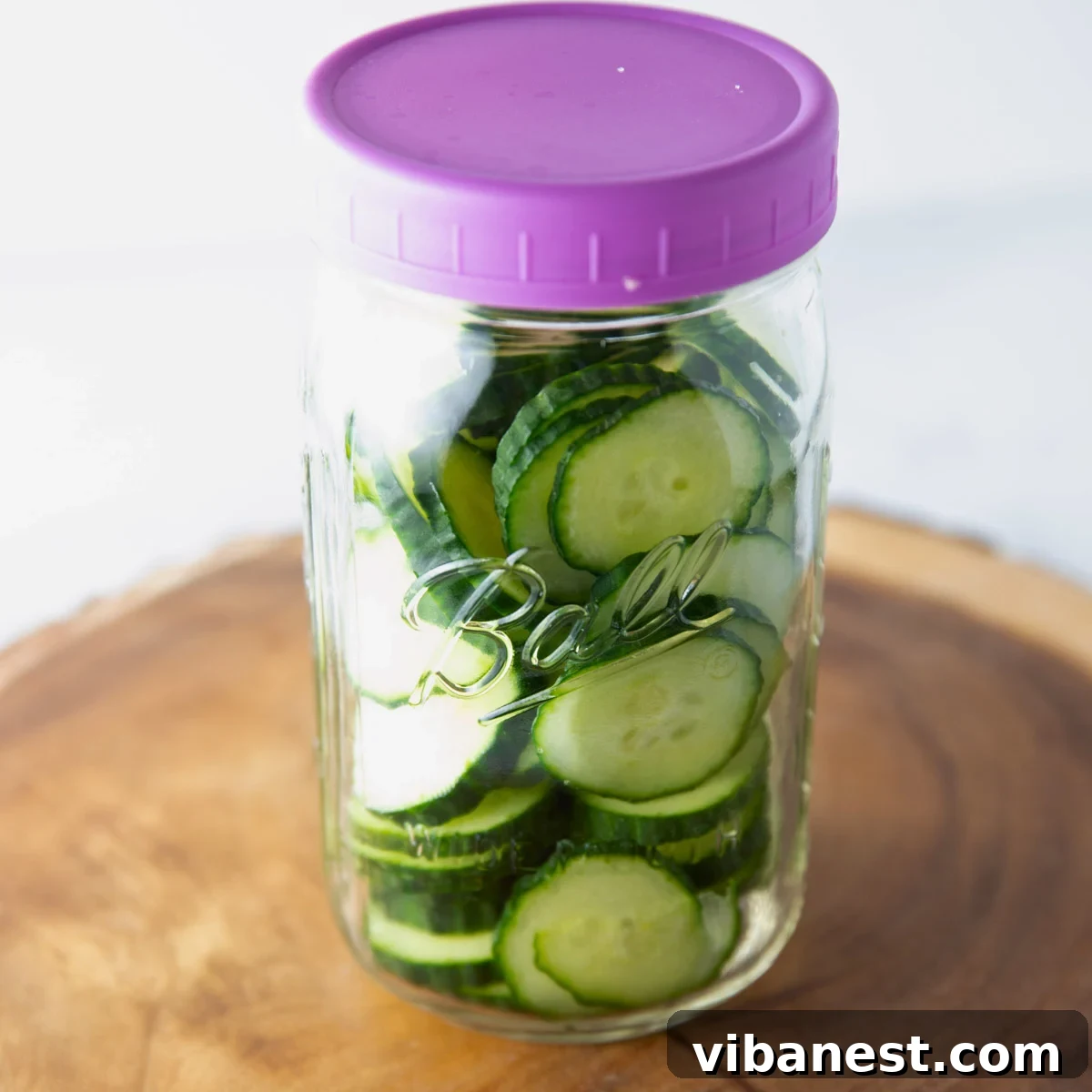 TikToks Viral Cucumber Salad Duet 7 A hand adding various dressing ingredients into a jar filled with sliced cucumbers for the viral salad.
