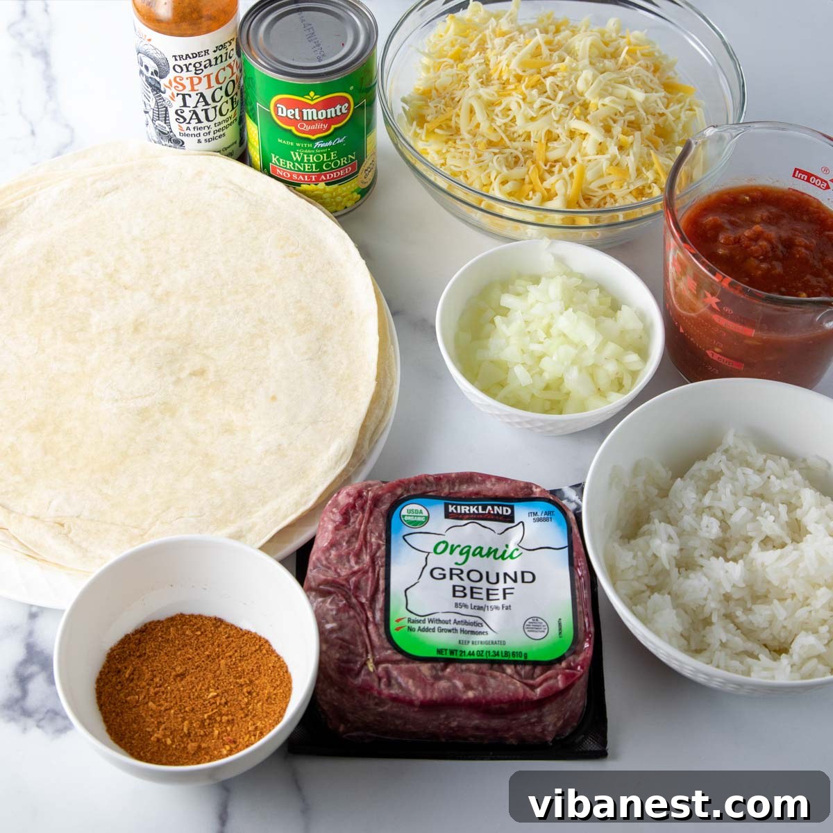 Effortless Enchilada Lasagna 3 Array of fresh ingredients laid out for making Mexican lasagna, including ground beef, tortillas, corn, and cheese.