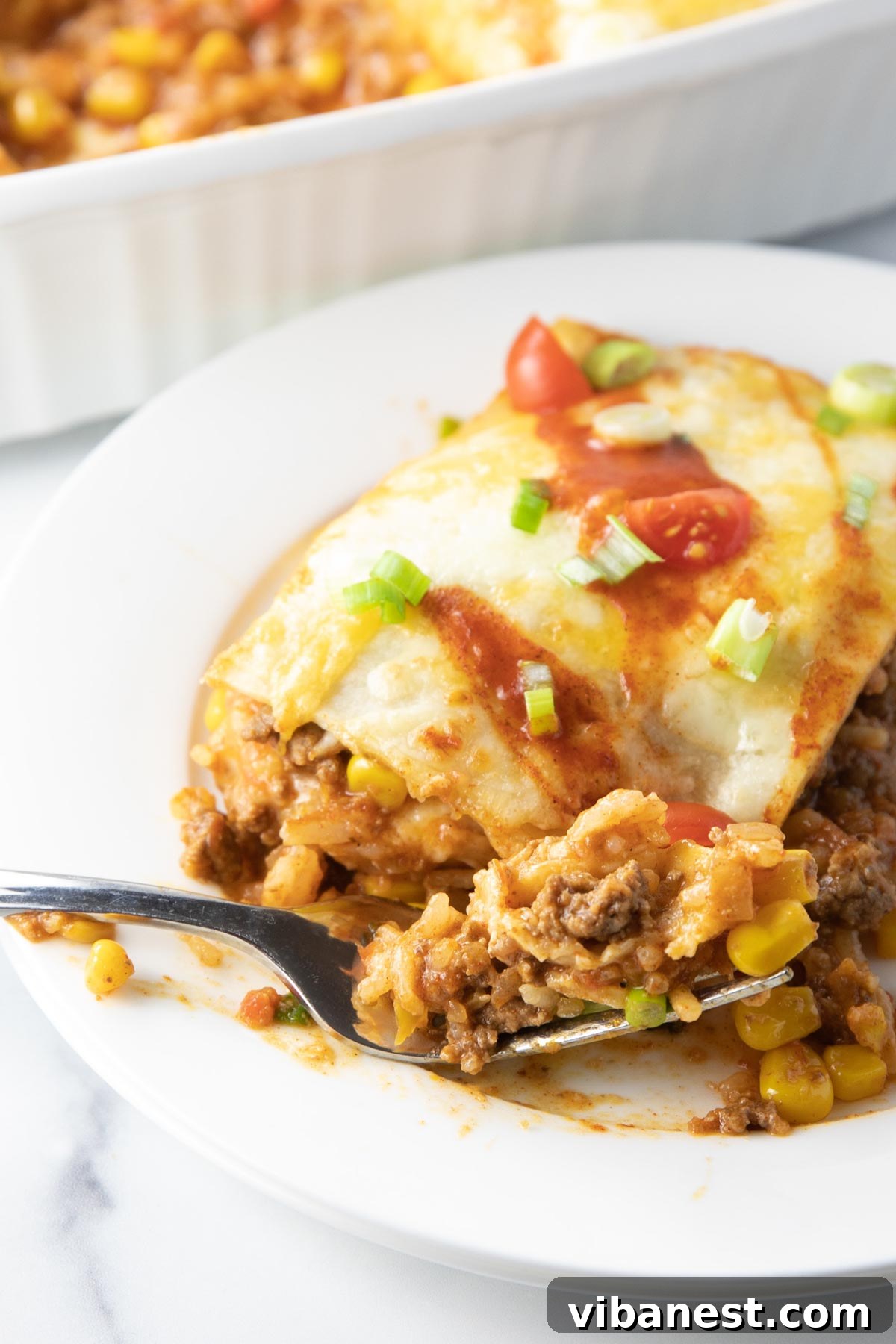 Effortless Enchilada Lasagna 6 Serving of Mexican lasagna garnished with sour cream, green onions, and tomatoes.