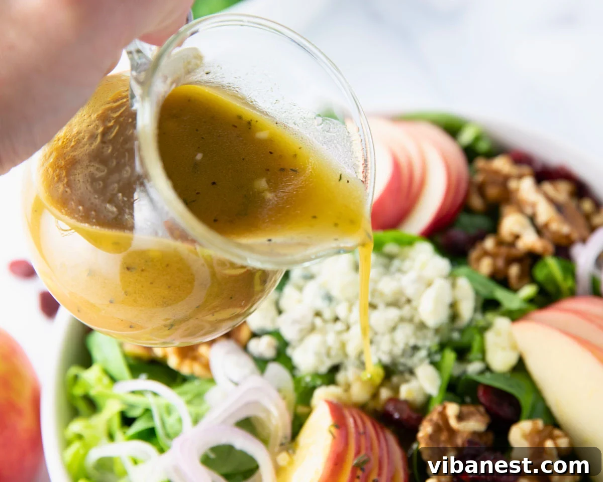 Crisp Apple Vinaigrette 7 A beautifully plated fall salad with mixed greens, crisp apple slices, dried cranberries, toasted walnuts, and a generous amount of apple cider vinaigrette drizzled on top.