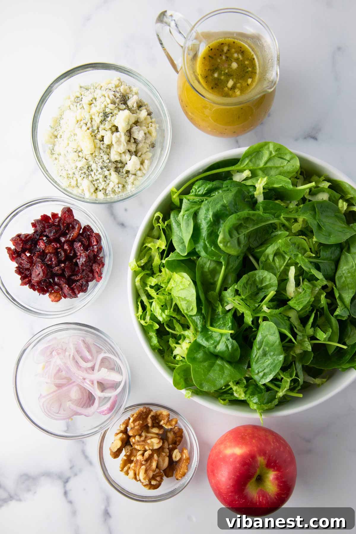 Autumn Abundance Bowl 4 A vibrant flat lay photo showcasing all the individual ingredients for the Fall Harvest Salad: greens, sliced apples, dried cranberries, walnuts, blue cheese, and shallots.