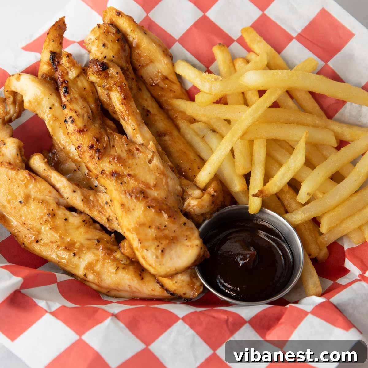Crispy Air Fryer BBQ Chicken Strips 2 Air Fryer'da mükemmel pişmiş, üzeri barbekü sosuyla kaplı tavuk parçacıklarının yakın çekimi, hızlı ve sağlıklı bir yemek olduğunu vurguluyor.