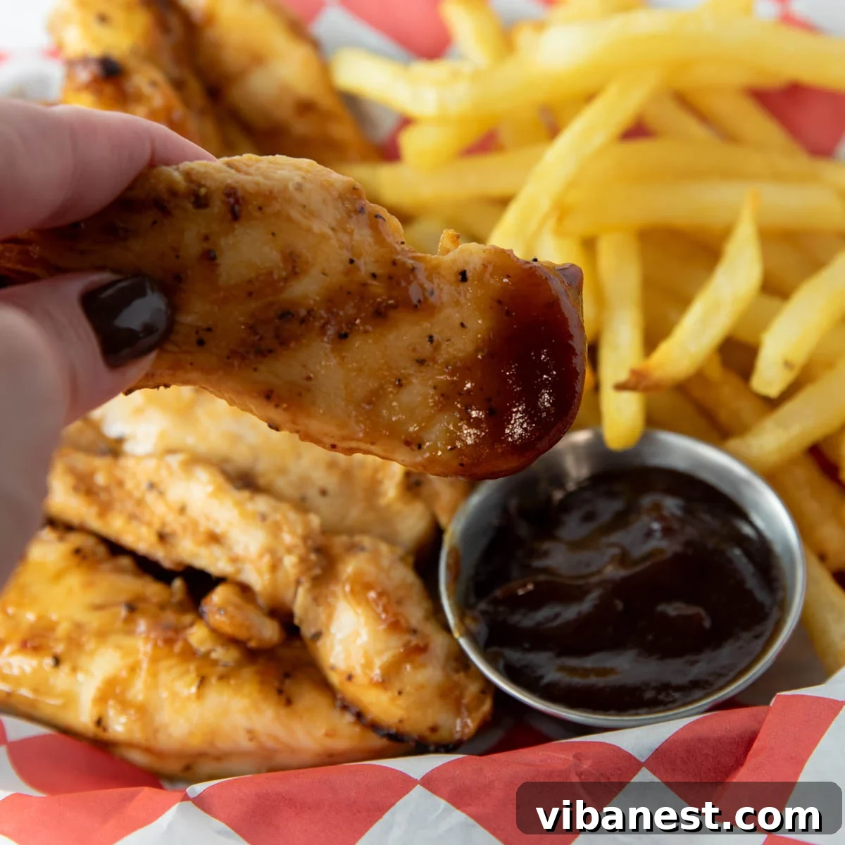 Crispy Air Fryer BBQ Chicken Strips 8 Yanında garnitürlerle birlikte bir tabak dolusu lezzetli air fryer barbekü tavuk parçacığı