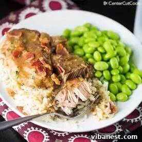 A plate of tender Slow Cooker Smothered Pork Chops served over fluffy rice with a side of green vegetables