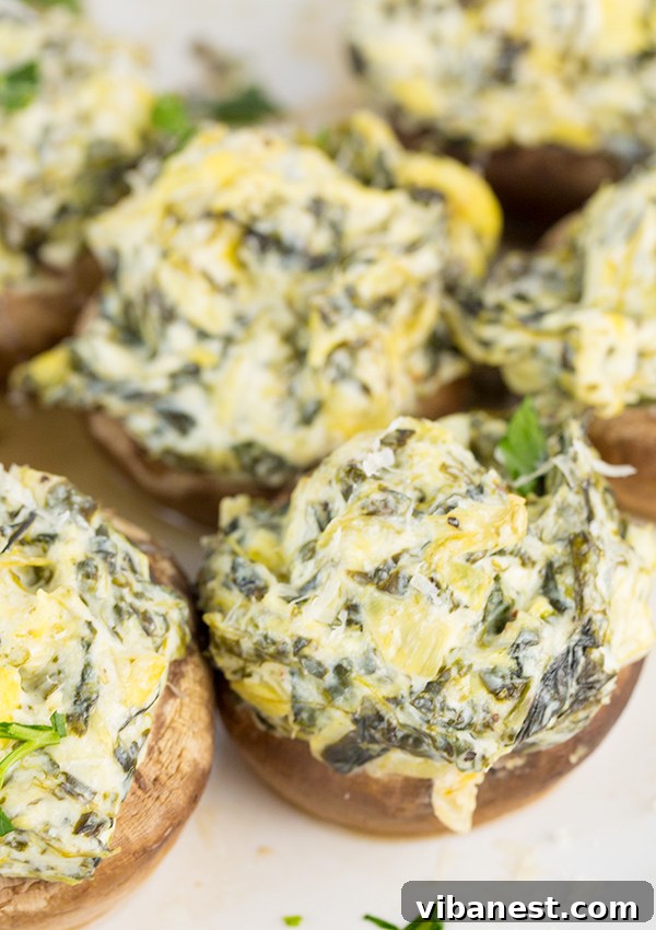 Spinach Artichoke Mushroom Poppers 4 Two spinach artichoke stuffed mushrooms arranged beautifully