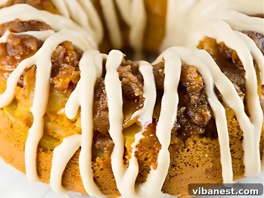 Harvest Spice Pumpkin Apple Cake 4 Close-up of a beautifully glazed pumpkin apple spice Bundt cake, showing the intricate fluted design and the creamy white drizzle.