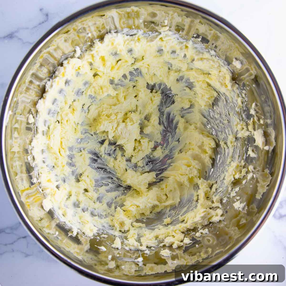 Irresistible Cream Cheese Frosting 6 Cream cheese and butter being whipped together in a bowl for the frosting base