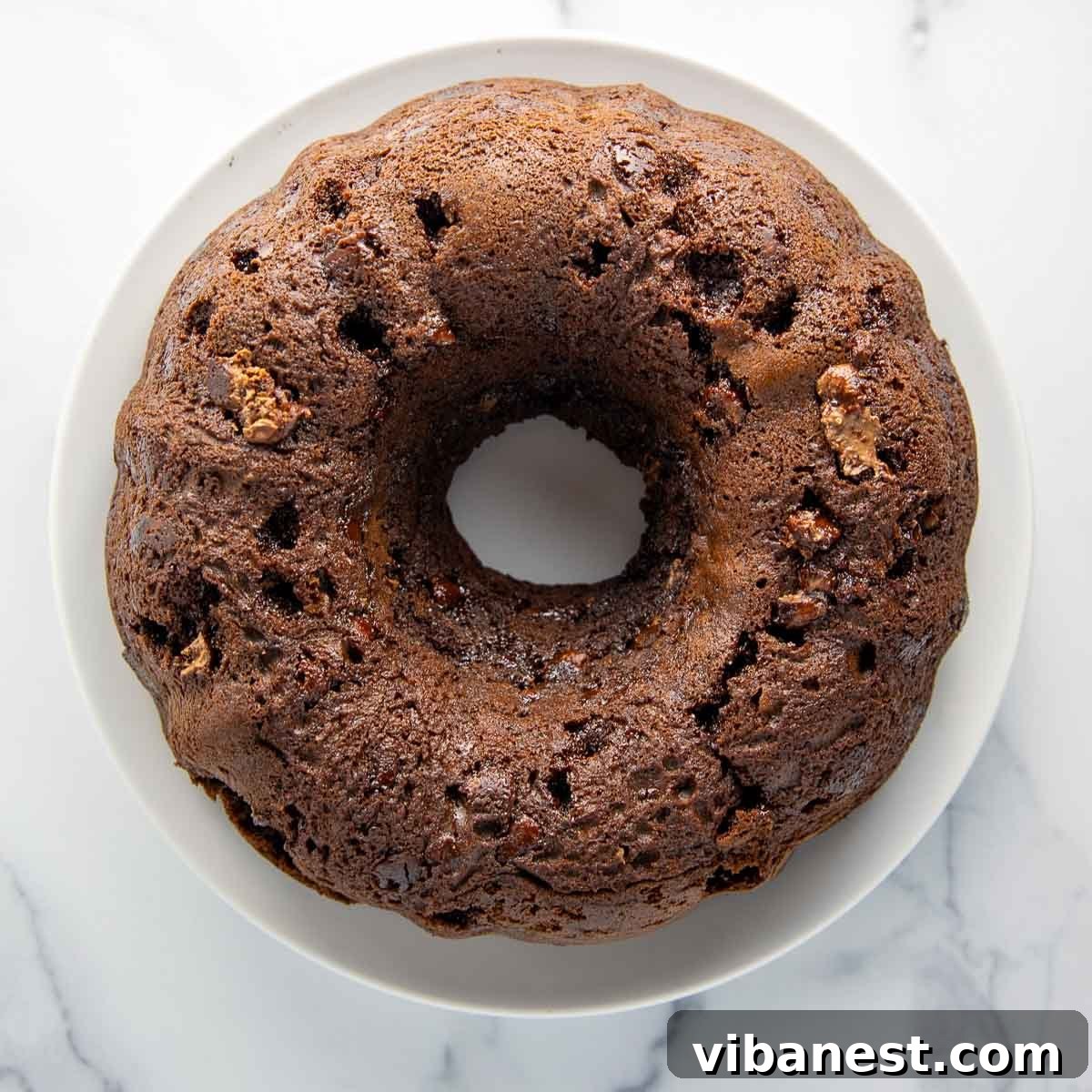 Decadent Double Chocolate Bundt Cake 13 A perfectly inverted chocolate bundt cake cooling completely on a white plate, its intricate design visible and awaiting frosting.