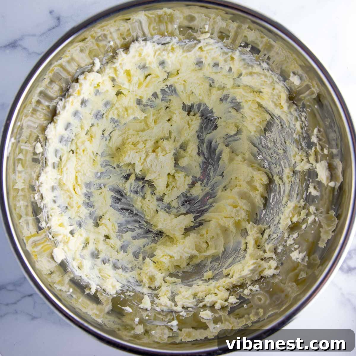 Decadent Double Chocolate Bundt Cake 14 Cream cheese and softened butter being beaten together in a mixing bowl to form the base of the creamy frosting.