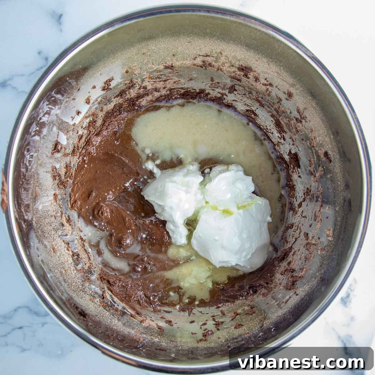 Decadent Double Chocolate Bundt Cake 9 Wet ingredients, including eggs, vanilla, sour cream, oil, and water, being added to the dry cake mix in a mixing bowl.