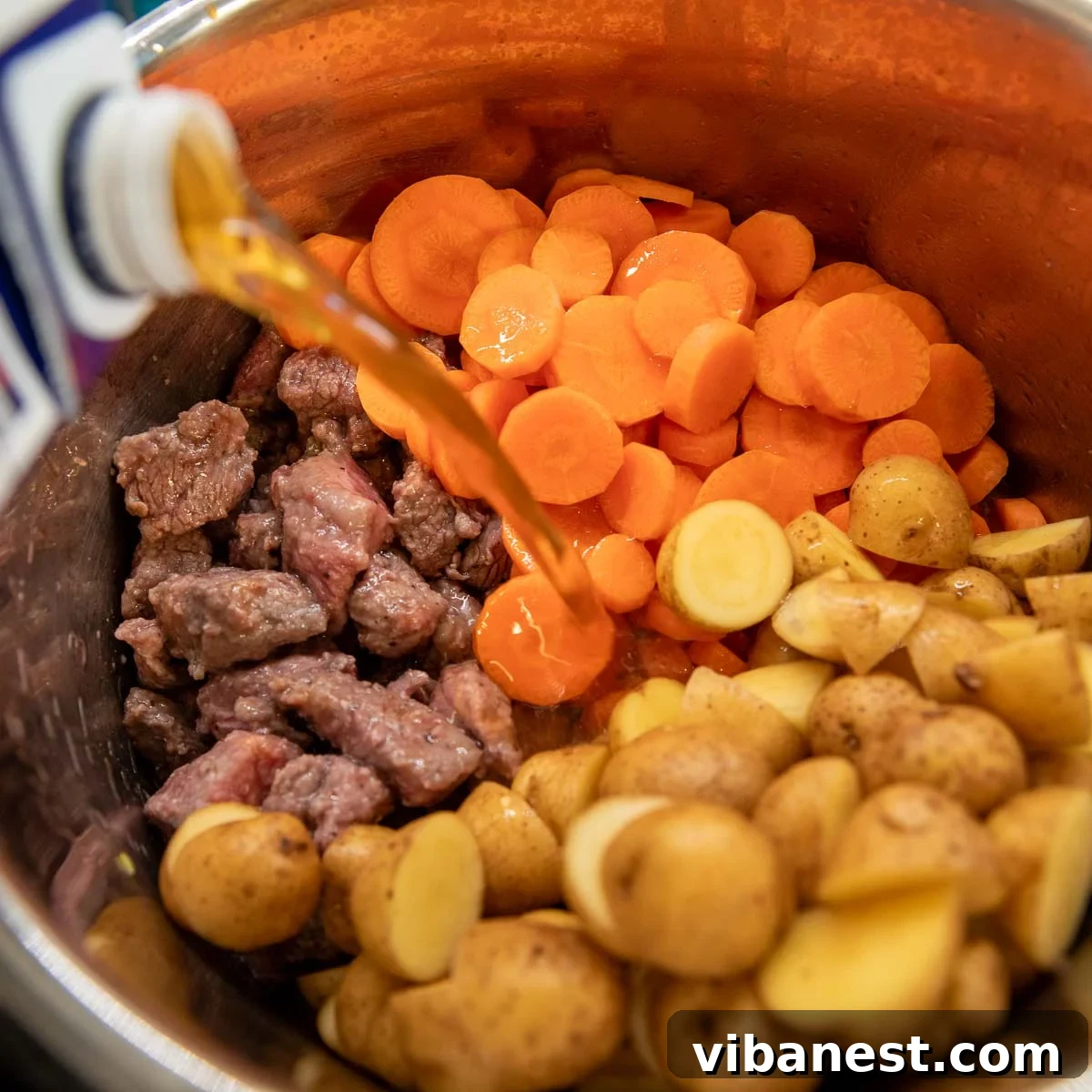 Instant Pot Irish Comfort Stew 11 Adding beef broth, potatoes, and carrots to the Instant Pot for pressure cooking.