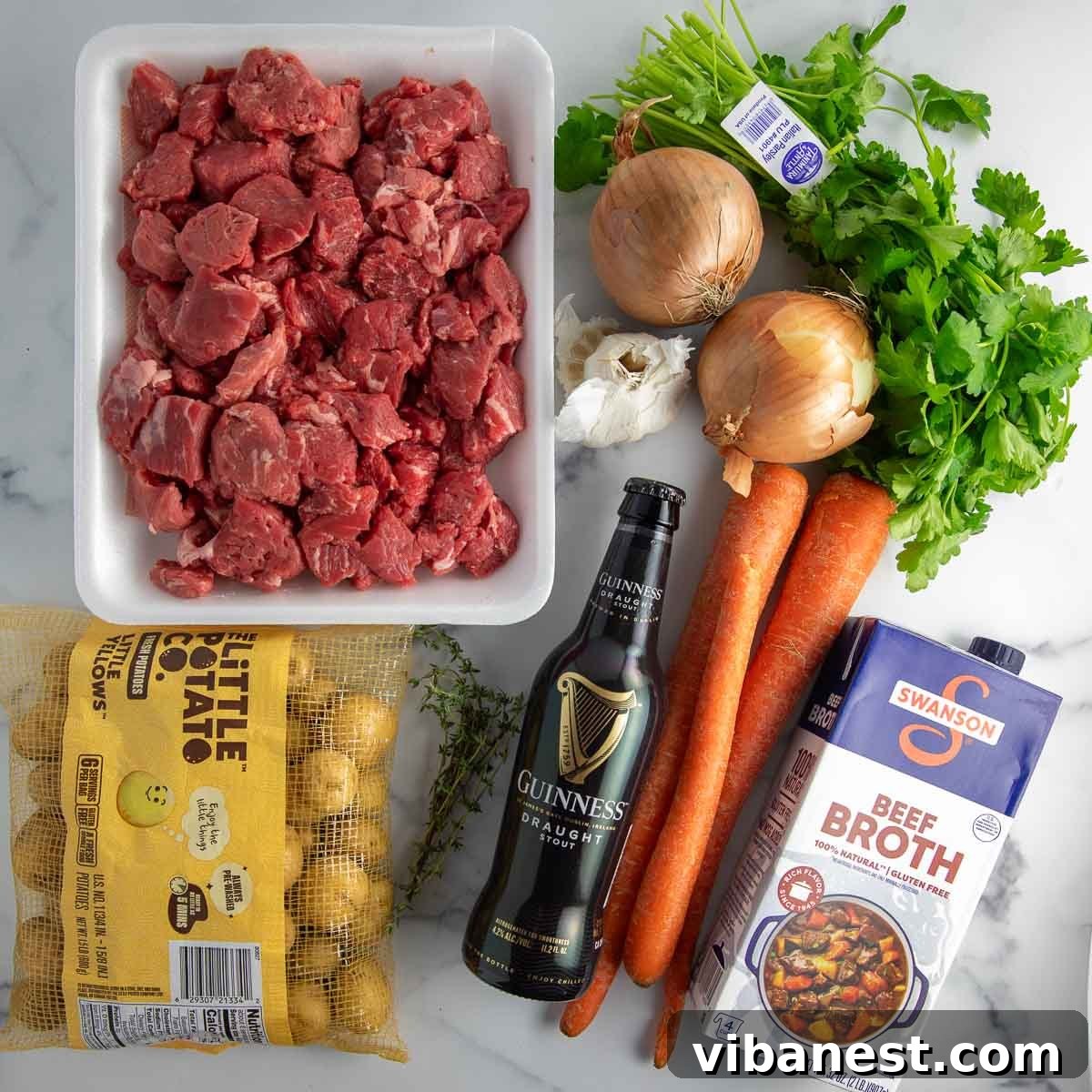 Instant Pot Irish Comfort Stew 5 Ingredients laid out for Instant Pot beef stew, including beef, vegetables, herbs, and Guinness.