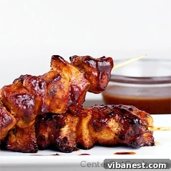 Close-up of freshly grilled BBQ Chicken Kabobs, coated in a luscious, sweet and savory barbecue sauce, garnished with fresh herbs.
