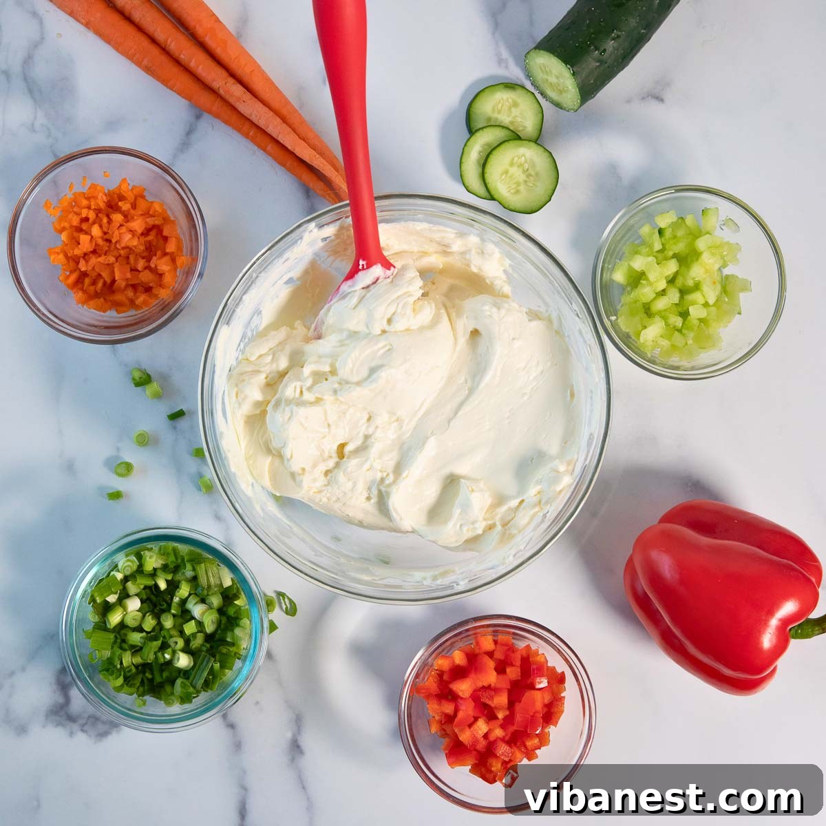 Garden Fresh Cream Cheese Veggie Spread 4 A collection of fresh ingredients laid out for homemade veggie cream cheese: cream cheese block, milk, chopped carrots, bell peppers, cucumber, and green onions.