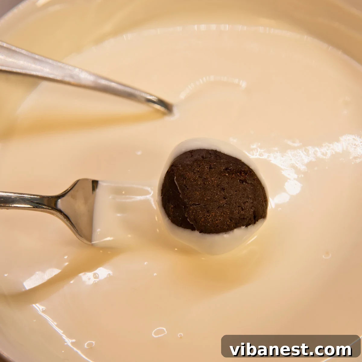 Effortless Holiday Oreo Delights 11 A fork holding a freshly dipped Oreo ball, allowing excess chocolate to drip away for a smooth finish.