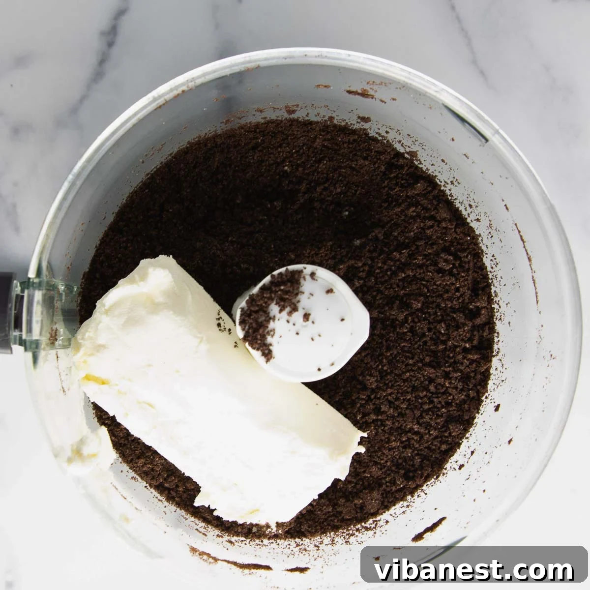 Effortless Holiday Oreo Delights 6 Cream cheese being added to crushed Oreos, ready to be blended into a smooth, truffle-making mixture.