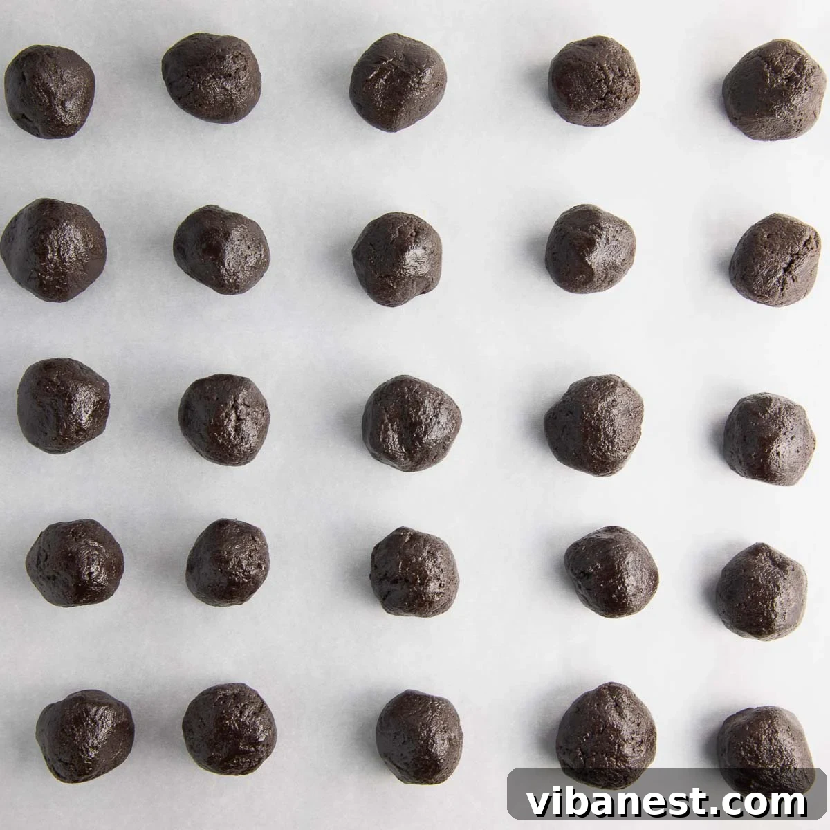 Effortless Holiday Oreo Delights 8 Rows of perfectly rolled Oreo balls, chilling on a parchment-lined baking sheet, awaiting their chocolate coating.
