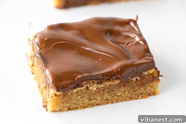 Freshly baked blondie bars topped with melted chocolate, cooling on a cutting board