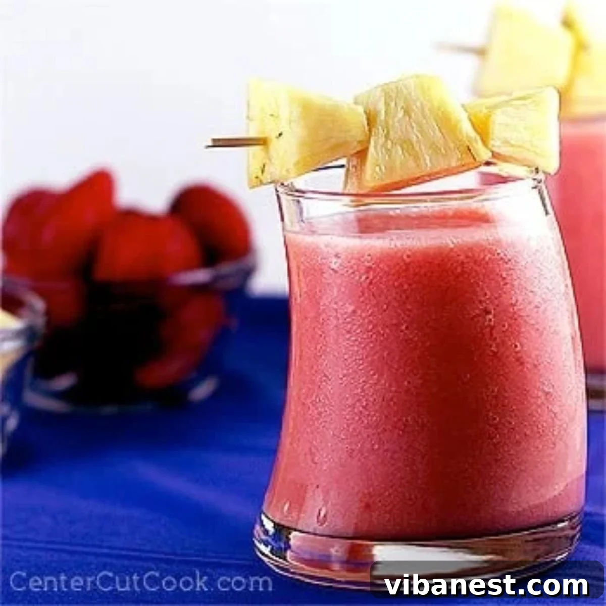 Tropical Berry Bliss 2 A refreshing strawberry pineapple smoothie in a tall glass, garnished with fresh fruit slices, ready to be enjoyed.