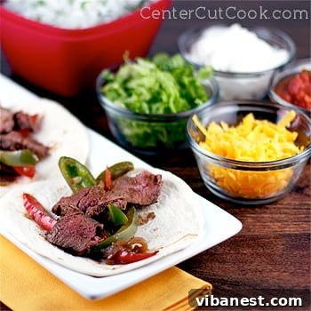 Close-up of cooked fajitas with perfectly grilled steak strips, colorful bell peppers, and onions, garnished with fresh lime