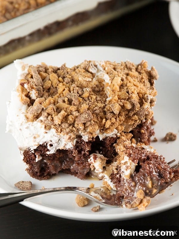 Easy Chocolate Caramel Toffee Poke Cake A close-up of a perfectly prepared Better Than Sex Cake, showing the smooth, creamy white topping dusted with crunchy Heath bar pieces.