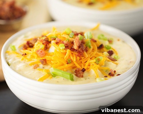 Recipe for Ultimate Loaded Baked Potato Soup A hearty bowl of Ultimate Loaded Baked Potato Soup, generously garnished with crispy bacon, melted shredded cheddar cheese, and fresh green onions.