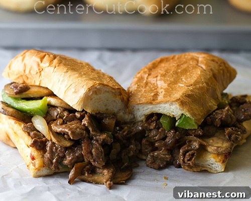 Authentic Philly Cheesesteak Sandwich Classic Philly Cheesesteak Sandwich loaded generously with thinly sliced steak, caramelized onions, and melted provolone cheese on a long hoagie roll.