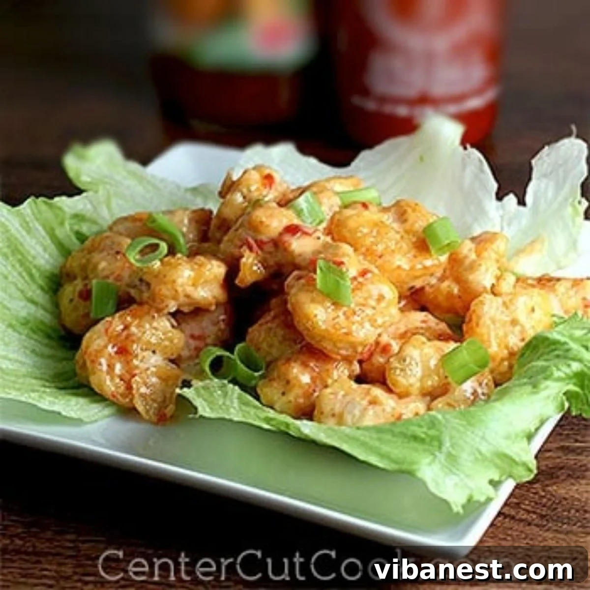 Bonefish Grill Copycat Bang Bang Shrimp 2 Crispy Bang Bang Shrimp served on a bed of fresh lettuce, garnished with green onions.