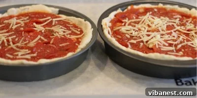 Deep Dish Pizza Assembly Deep dish pizza being assembled with cheese, sauce, and toppings