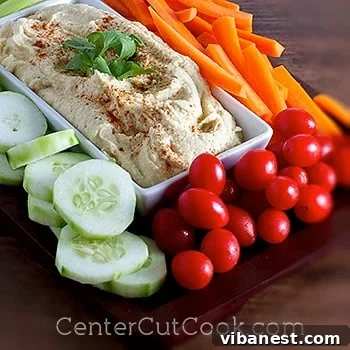 Homemade Hummus Close-up A close-up shot of creamy, homemade hummus in a white bowl, garnished with a sprinkle of paprika and a fresh parsley leaf.