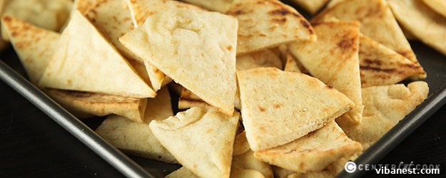Golden-brown homemade pita chips arranged on a platter, ready for dipping.